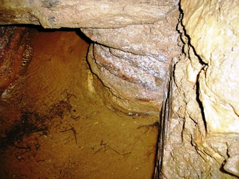 View of a channel on the bottom of a qanat tunnel with CaCO3 deposits (in white color).